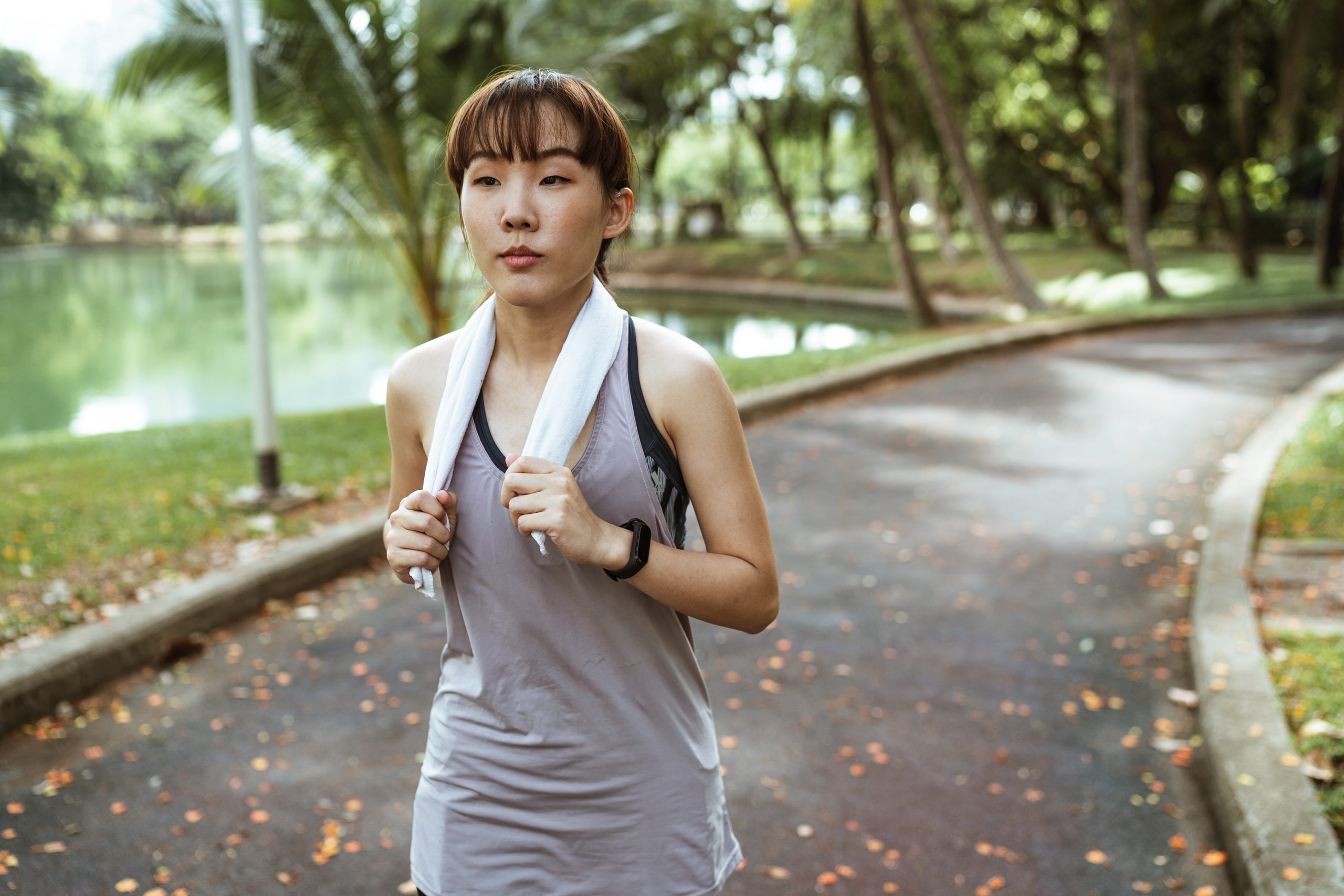 Confident woman with towel running in park