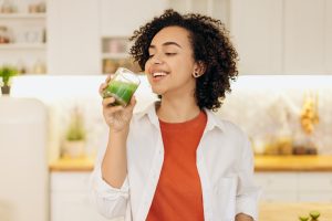 a woman drinking a glass of Duckweed Green Shake