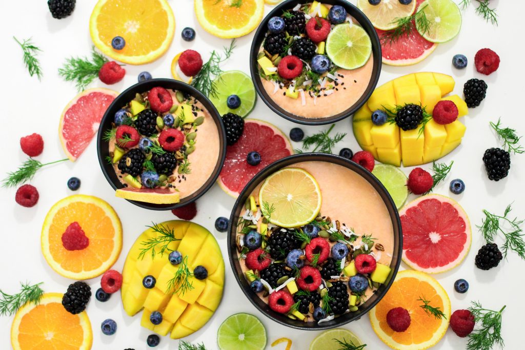 A photo of a fruit bowl overflowing with berries, citrus fruits, bananas, and other fruits