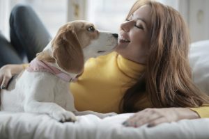 A close-up photo of a person's face smiling warmly down at a dog