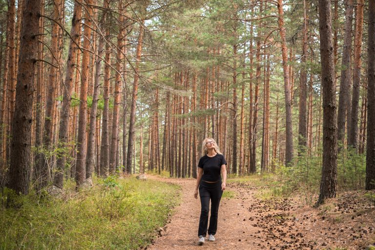 Forest baths, an adult woman walks through a pine forest, restoring health and psyche in nature images