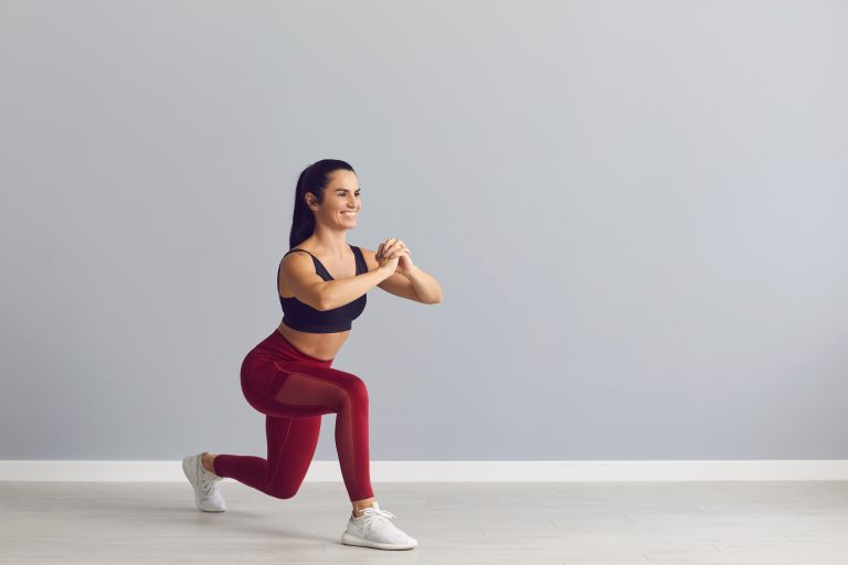 Smiling fitness trainer showing how to do fitness exercise