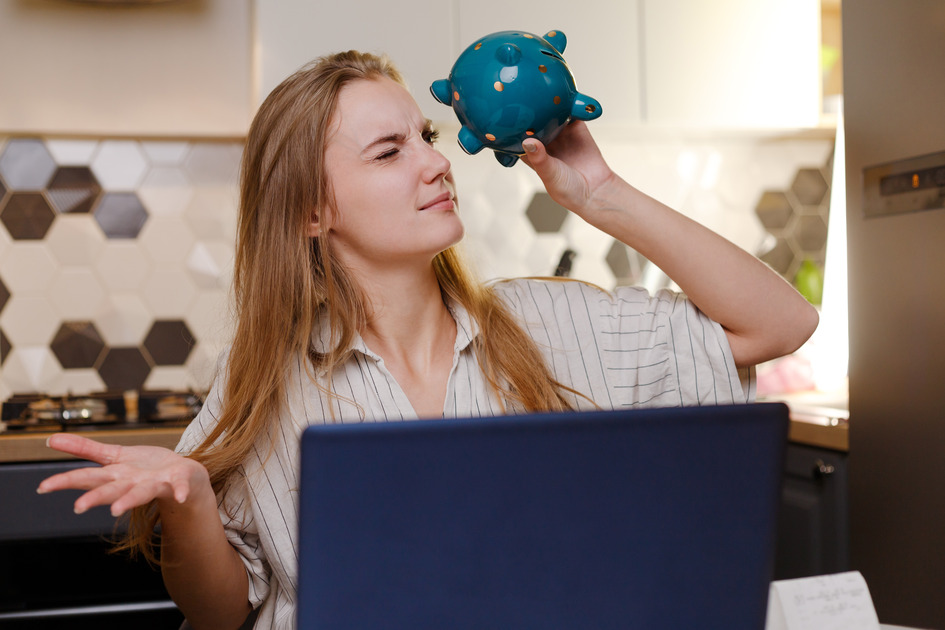 woman-looking-at-empty-piggy-bank-sitting-at-home