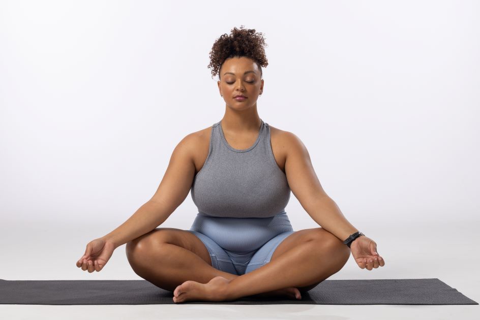 Biracial-young-female-plus-size-model-practices-yoga-on-white-background