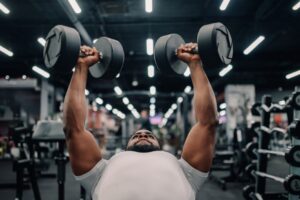 Determined-bodybuilder-lifting-heavy-dumbbells-in-modern-gym