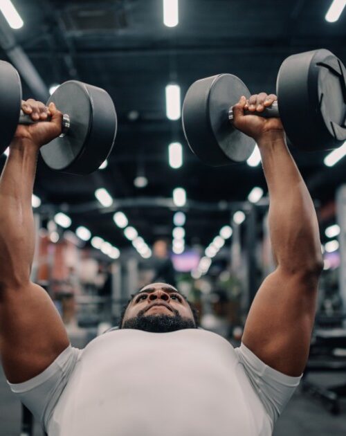 Determined-bodybuilder-lifting-heavy-dumbbells-in-modern-gym