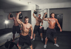 Four muscular guy exercising with lifting weights in a gym club.