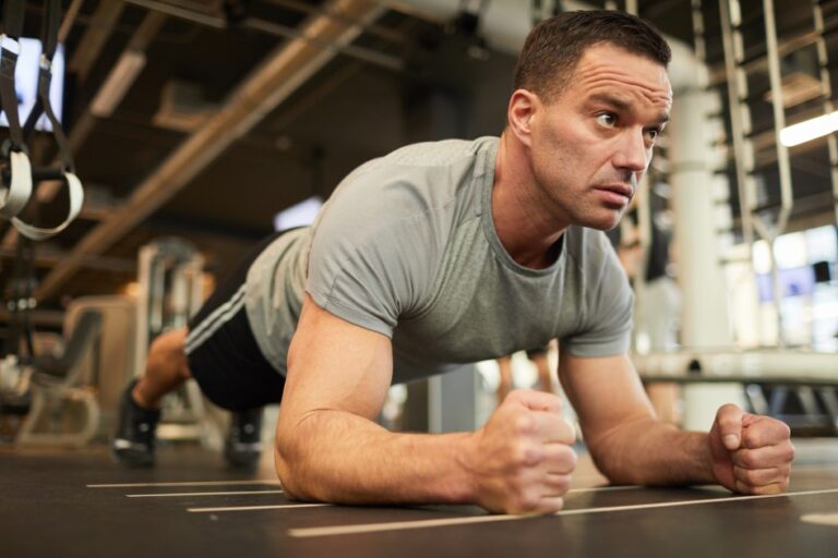 Muscular Man Doing Plank Exercise in Gym