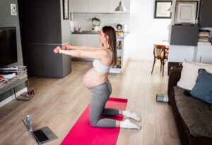 pregnant-woman-exercising-on-yoga-mat-in-living