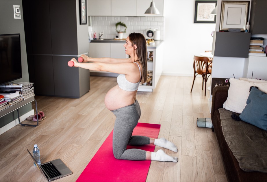pregnant-woman-exercising-on-yoga-mat-in-living
