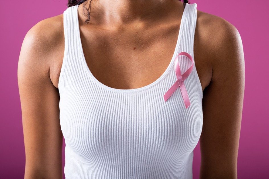 Midsection of african american mid adult woman with pink breast cancer awareness ribbon on tank top