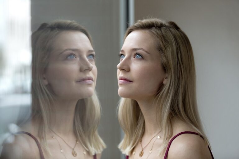 Portrait of blond young woman and her reflection on windowpane