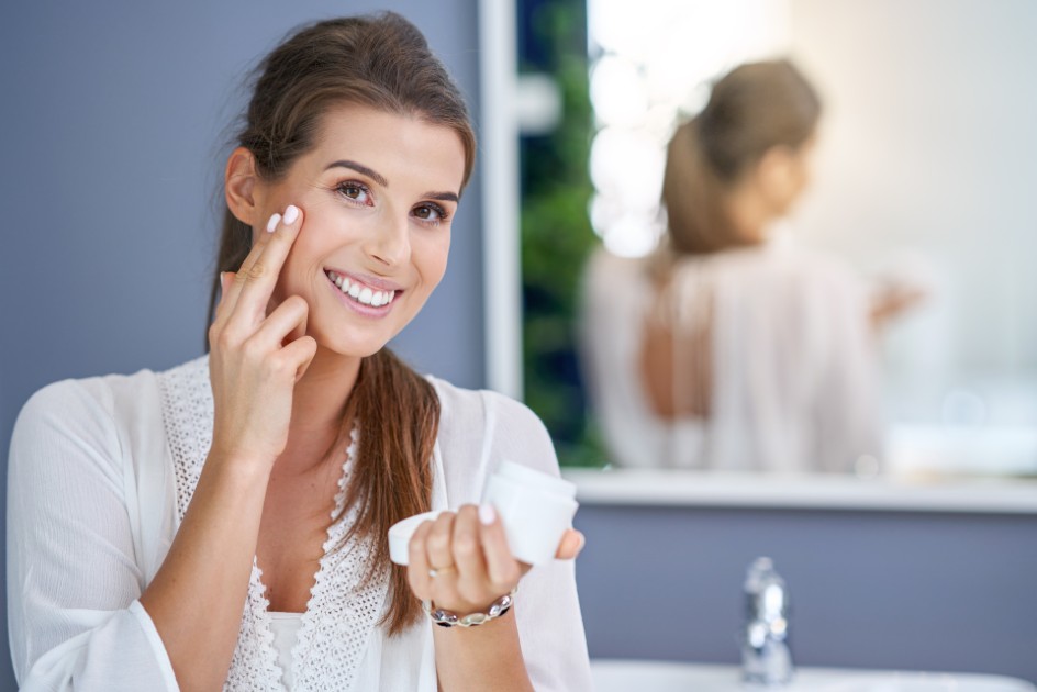 Beautiful-brunette-woman-applying-face-cream-in-the-bathroom