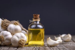 Fresh garlic and garlic oil on the wooden background