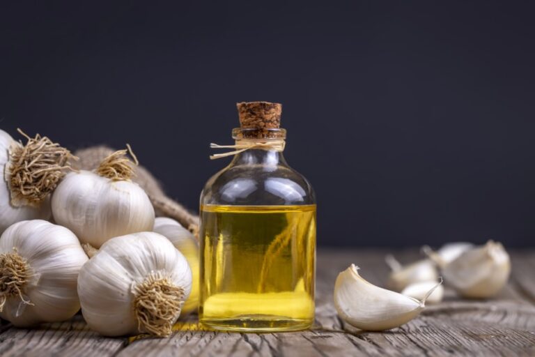 Fresh garlic and garlic oil on the wooden background