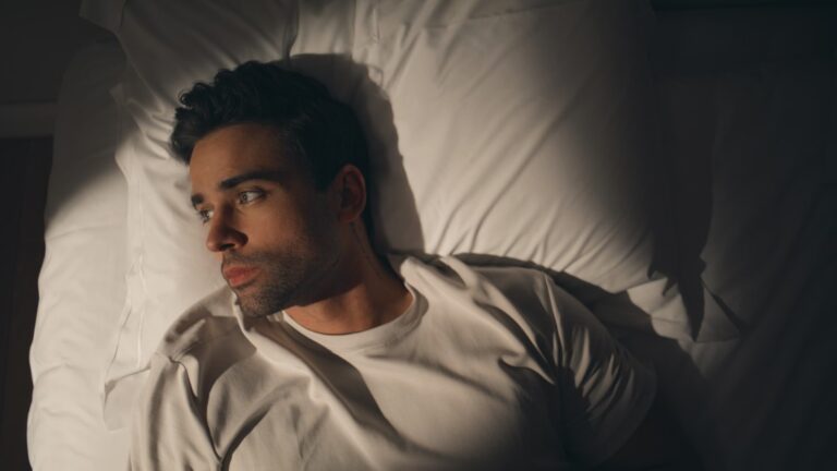 Man-lying-night-bed-suffering-from-insomnia-closeup-top-view.-Sad-guy-on-pillow