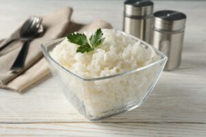 Composition with bowl of delicious rice on wooden background, closeup