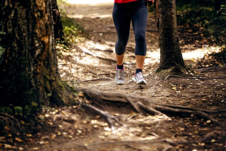 Person-walking-briskly-on-a-tree-lined-path-in-natural-daylight