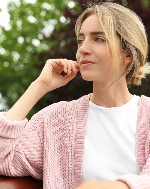 Beautiful young woman sitting on bench in park