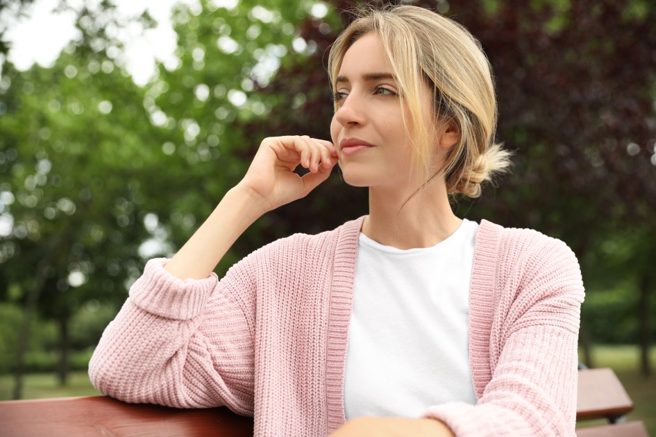 Beautiful young woman sitting on bench in park