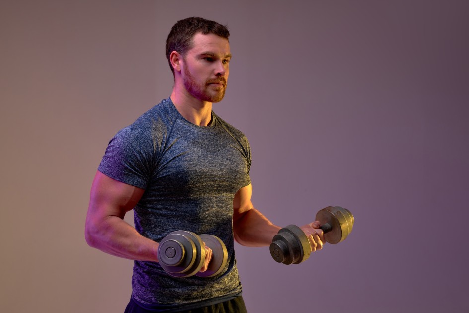 Man Working Out Lifting Dumbbells in Fitness Studio