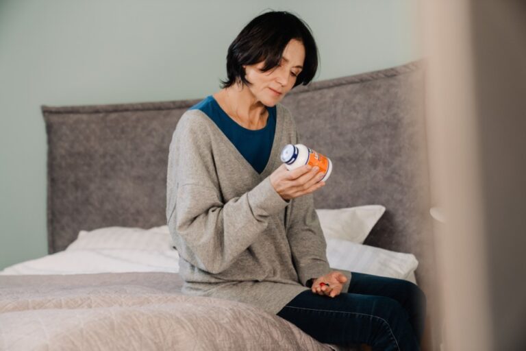 Woman Sitting on Bed with Medicine Bottle