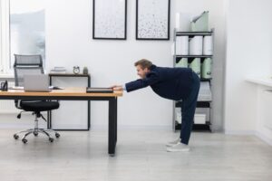 Young-businessman-doing-stretching-exercise-in-office