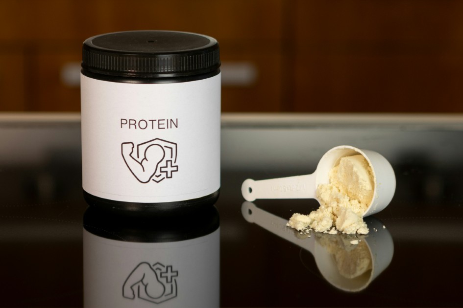 Vanilla protein supplement jar and scoop, muscle recovery and fitness.